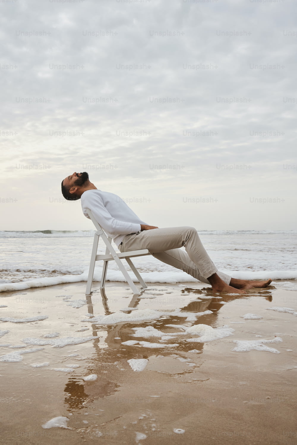 Ein Mann sitzt auf einem Stuhl am Strand