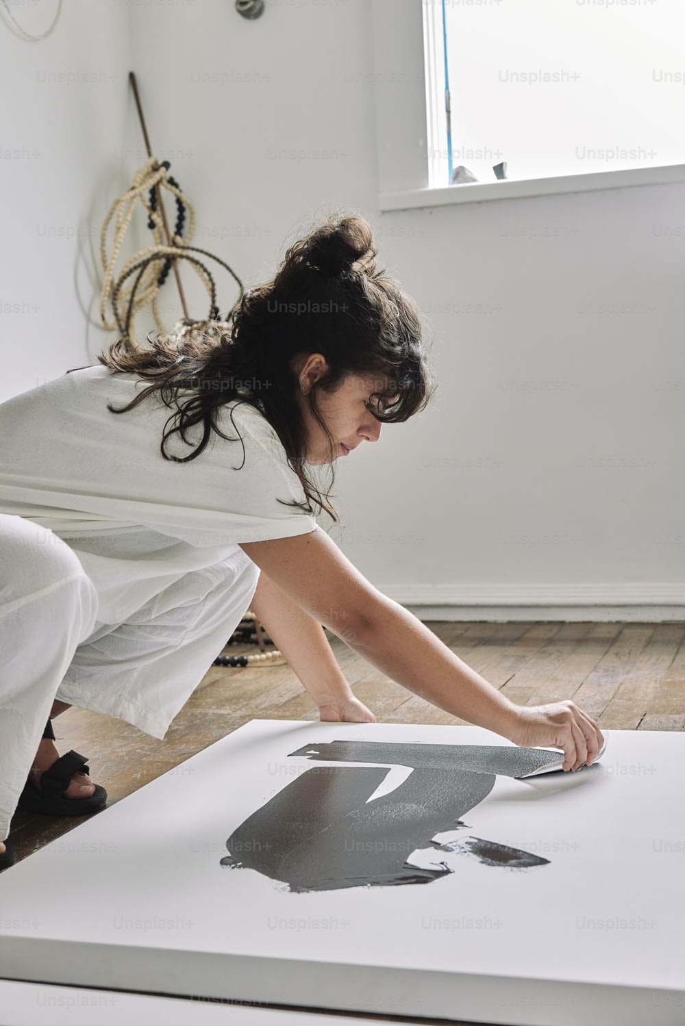a woman in a white dress is painting a picture