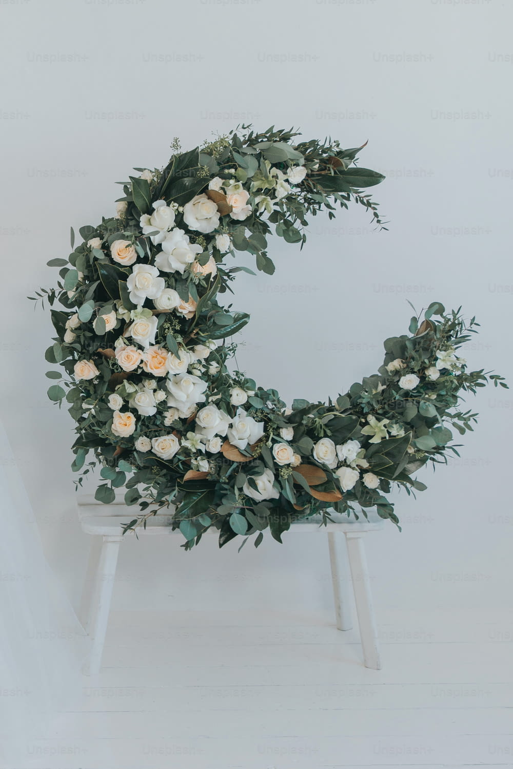 a white flower wreath on a white chair