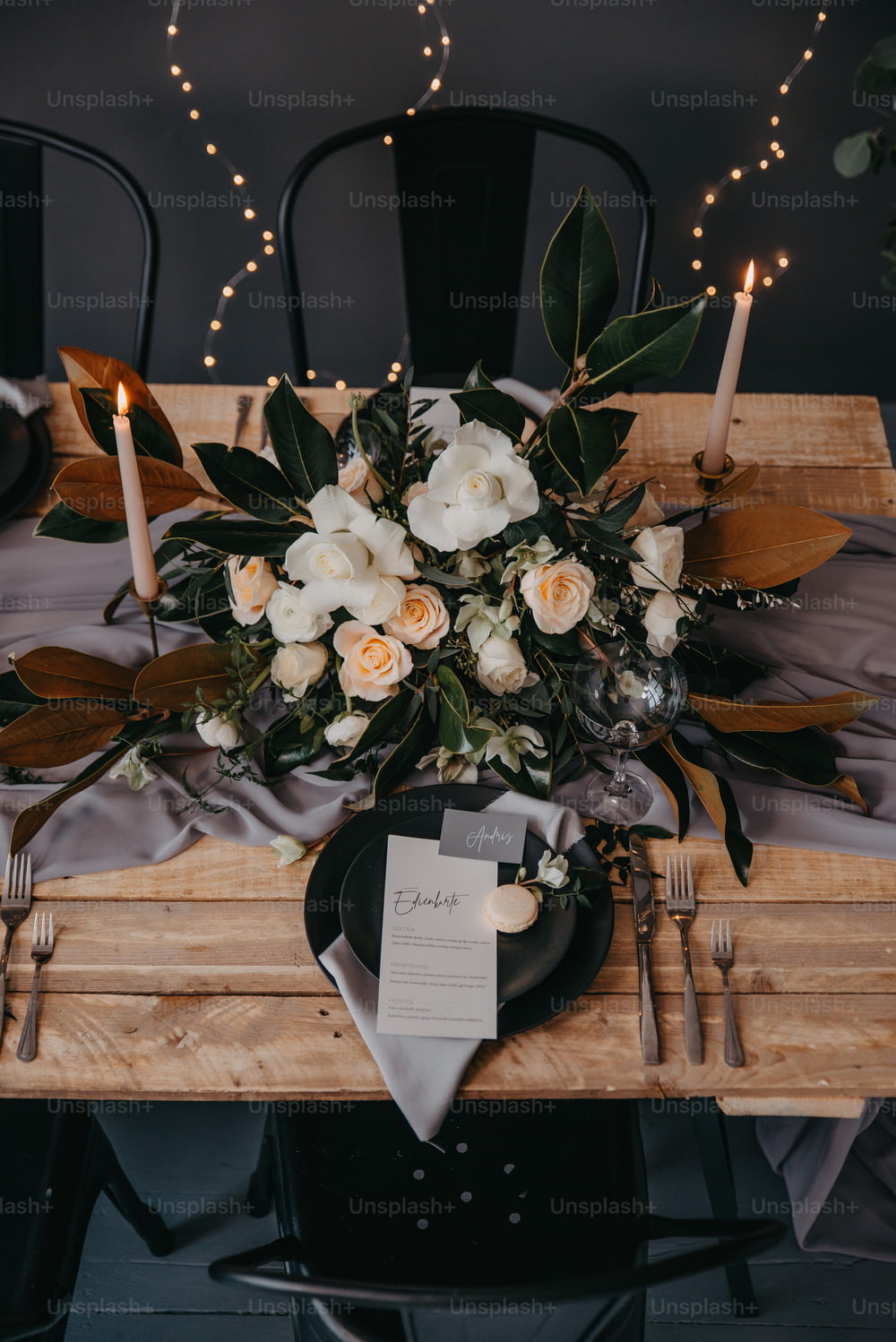a wooden table topped with a black plate and a bouquet of flowers