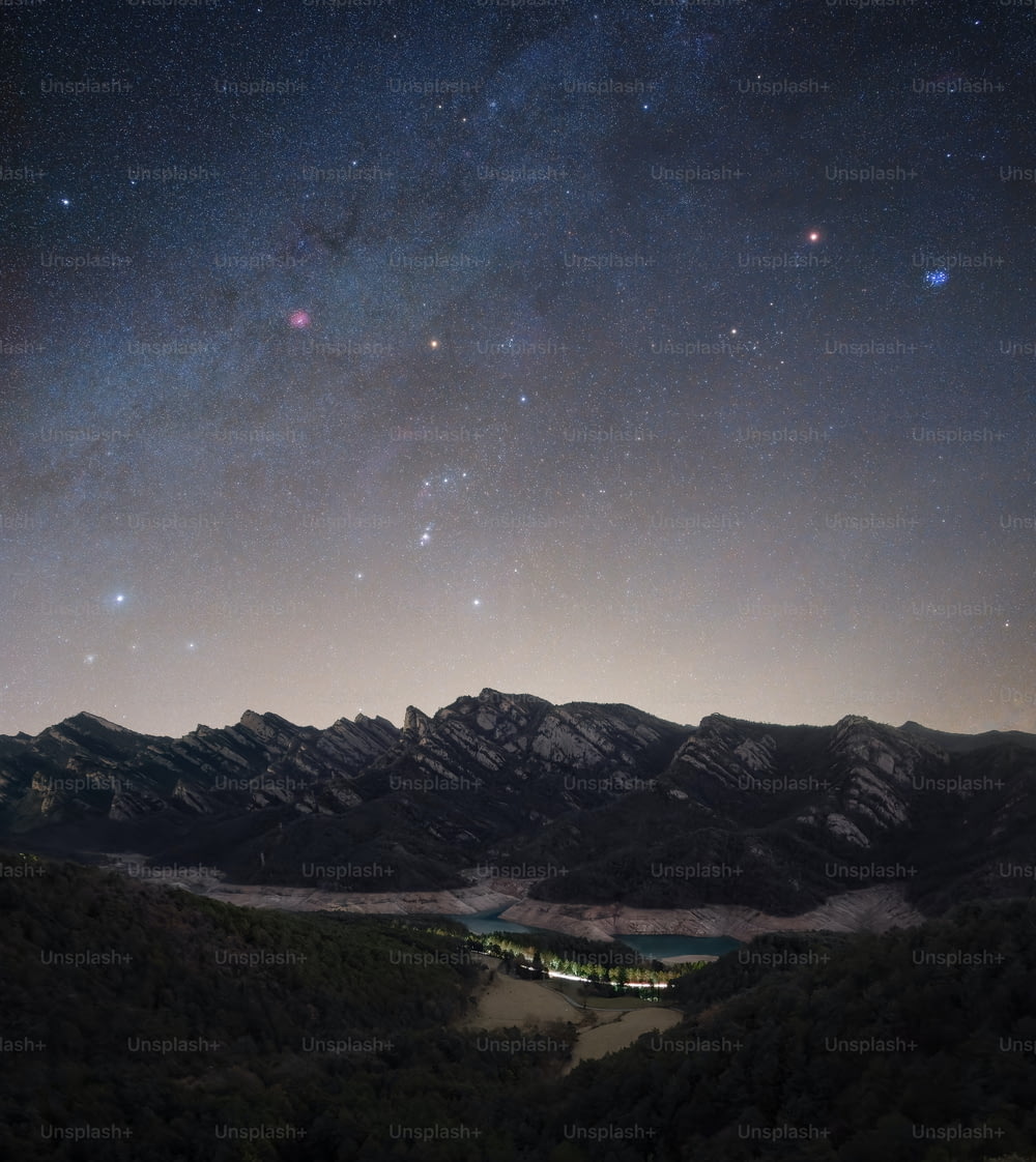 the night sky with stars above a mountain range