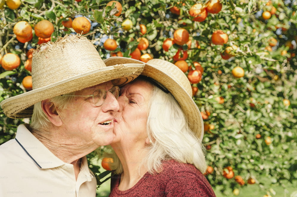 um homem e uma mulher se beijando na frente de uma laranjeira