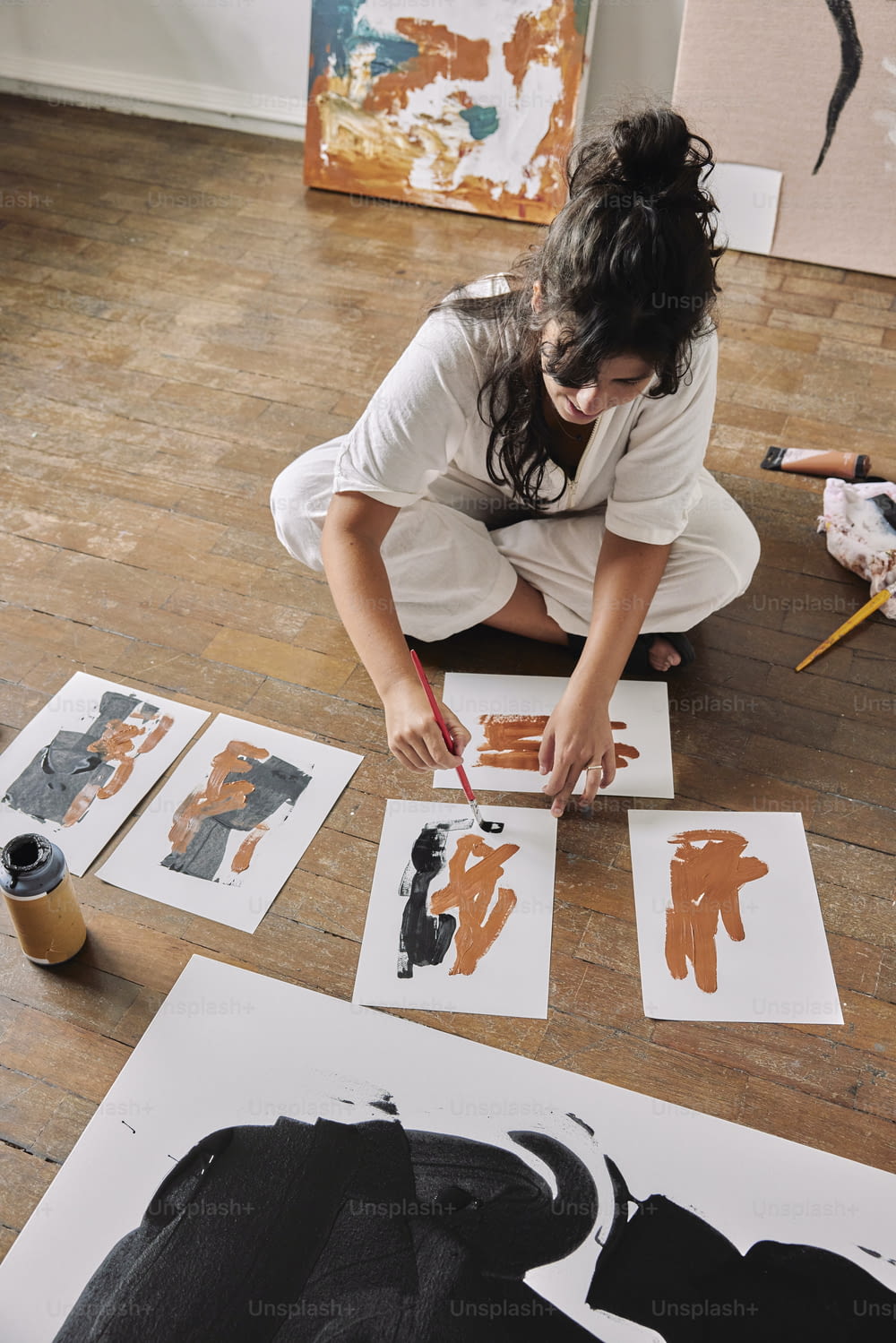 a woman sitting on the floor working on some artwork
