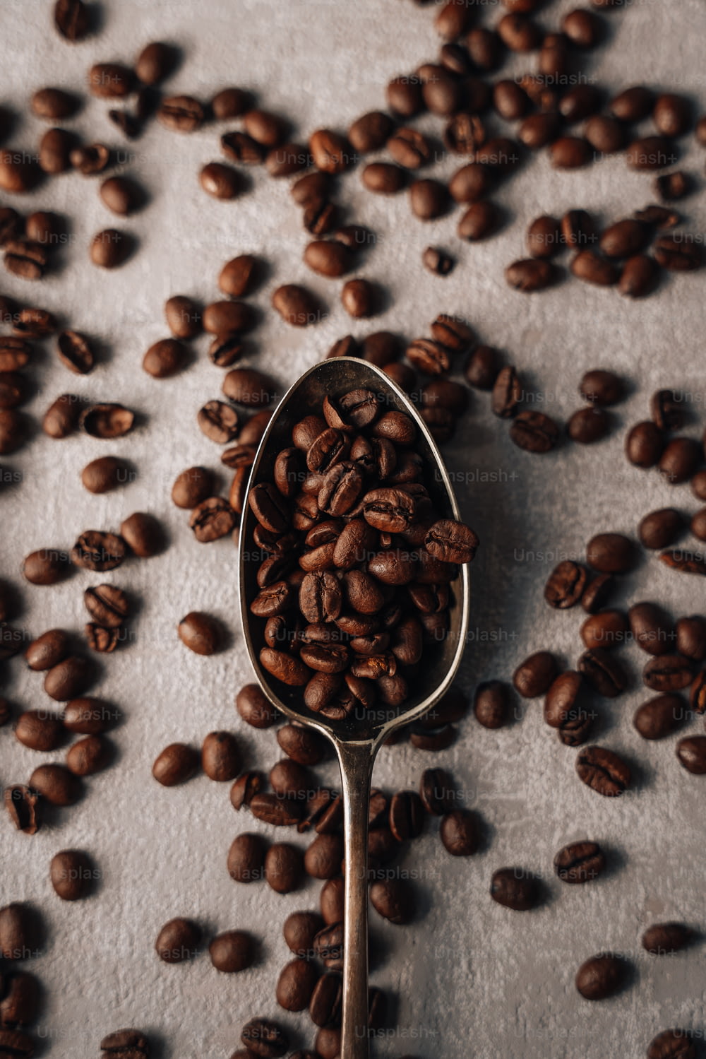 a spoon filled with coffee beans on top of a table