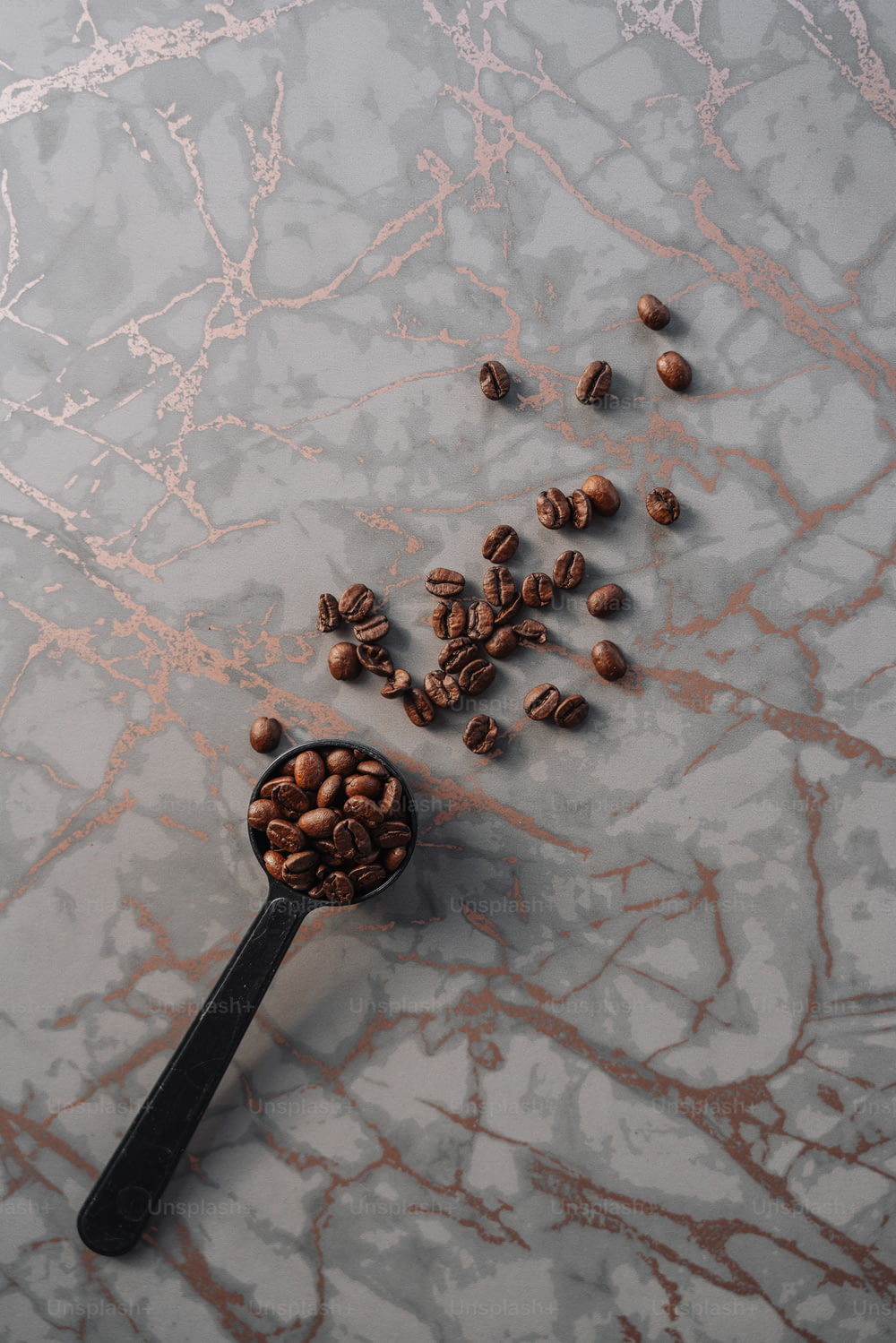 un cucchiaio pieno di chicchi di caffè su una superficie di marmo