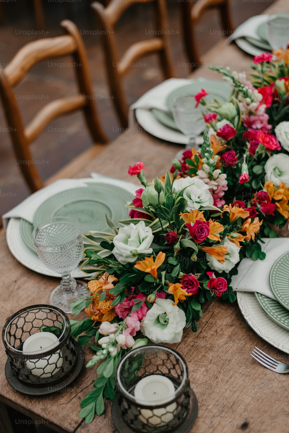 a wooden table topped with plates and flowers