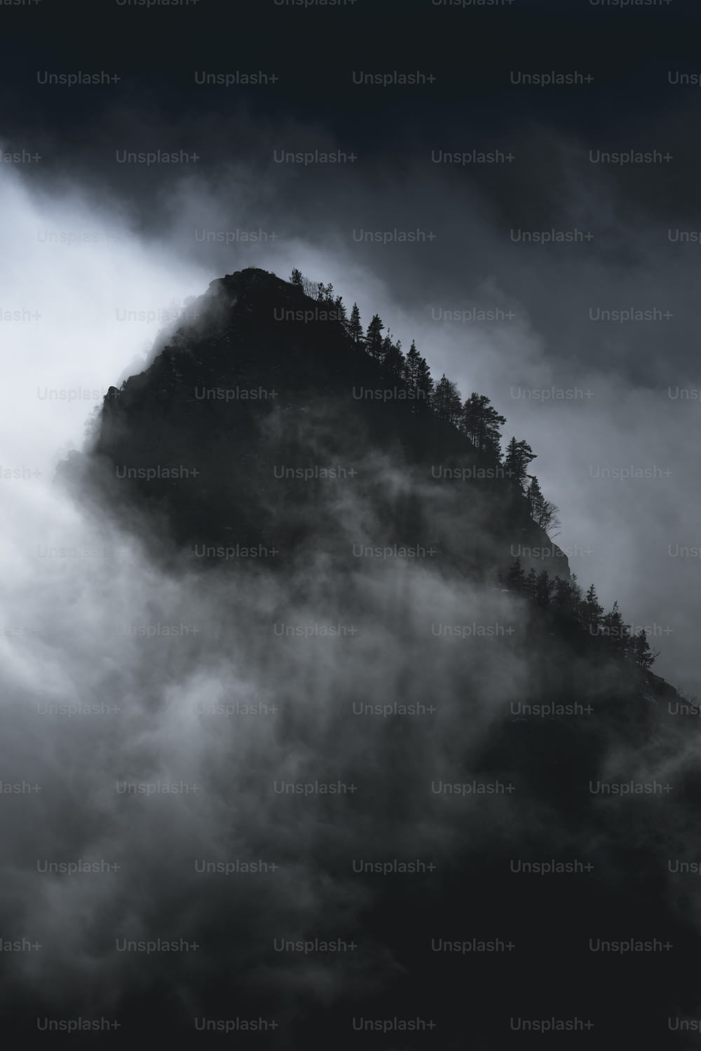 Une photo en noir et blanc d’une montagne couverte de nuages