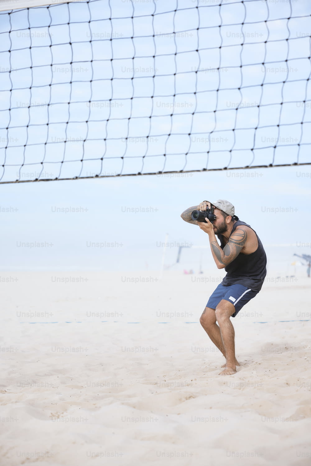 a man standing on a beach next to a volley ball net