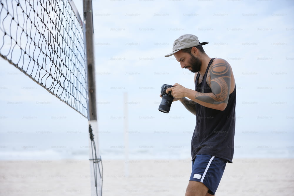 a man holding a camera near a volleyball net