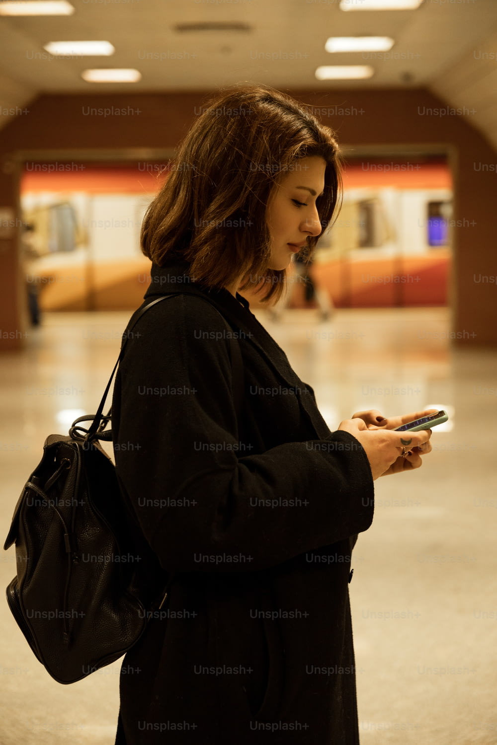 a woman standing in a building looking at her cell phone