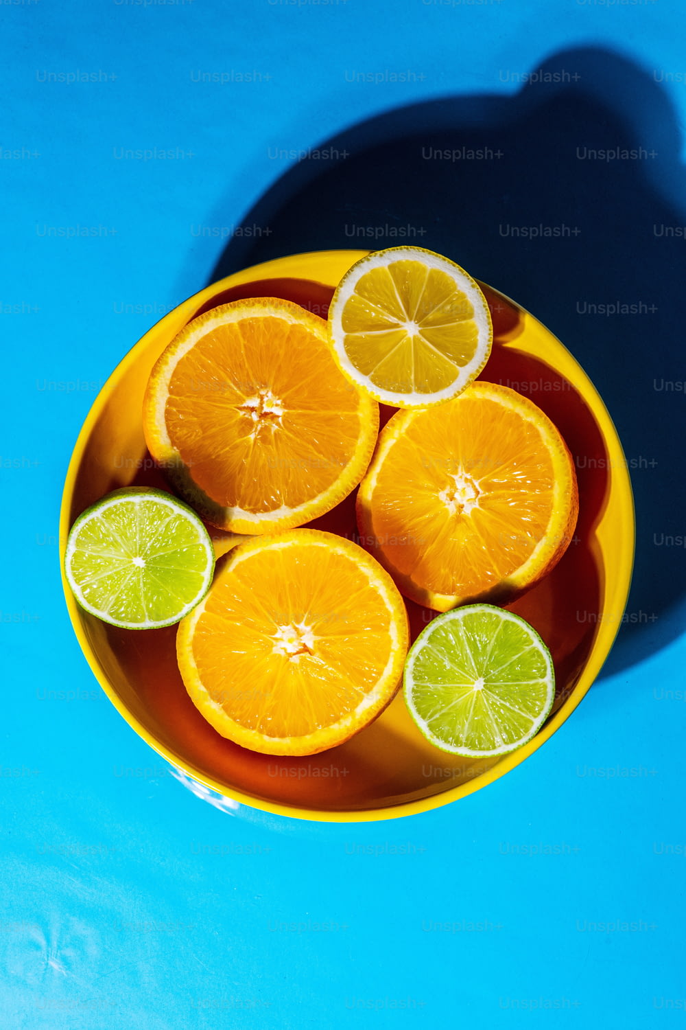 a yellow bowl filled with sliced oranges and limes