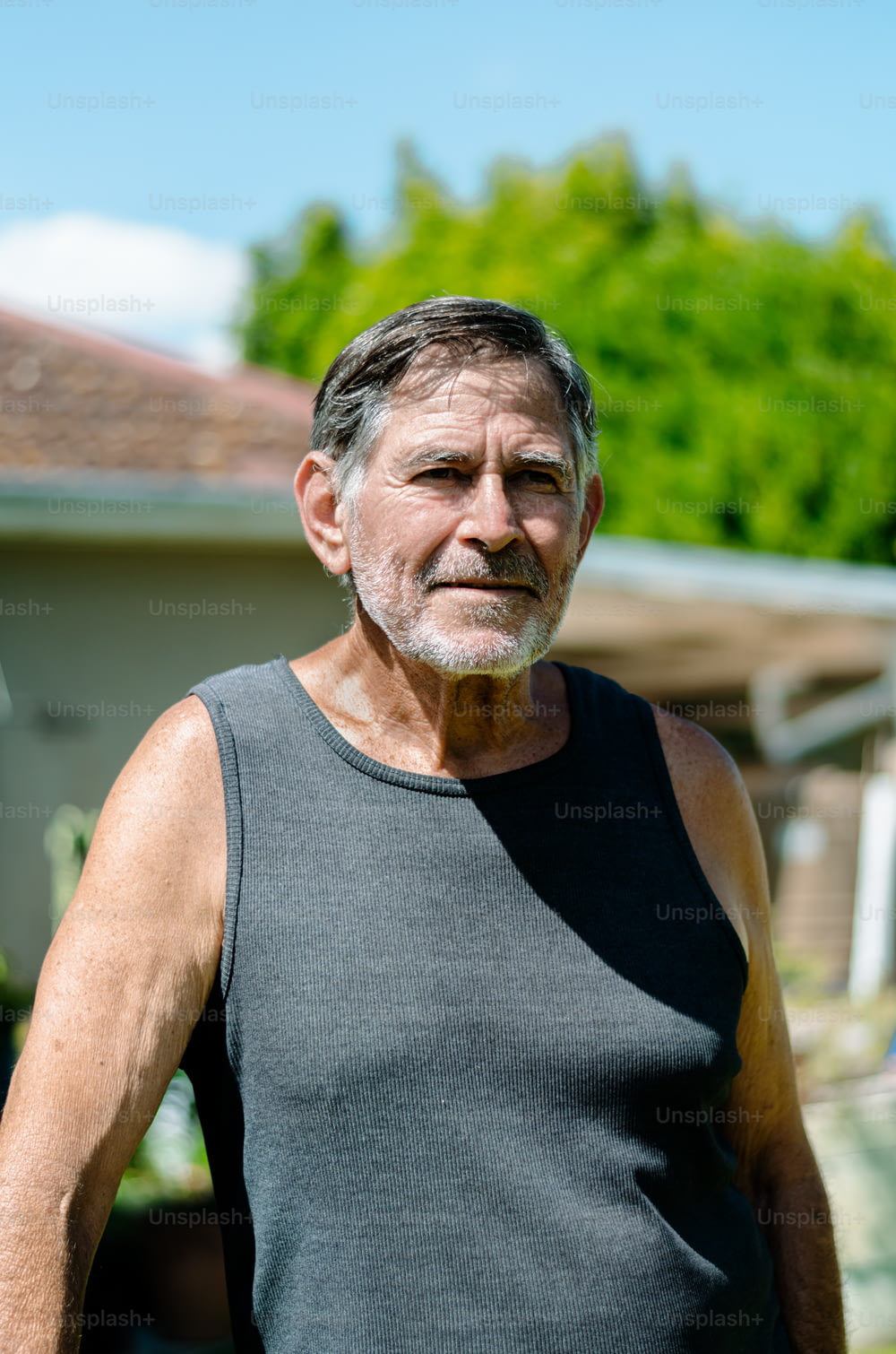 un vieil homme debout devant une maison