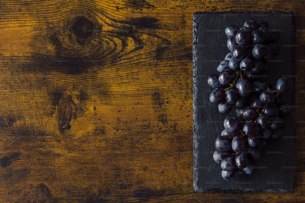 a bunch of grapes sitting on top of a slate slab