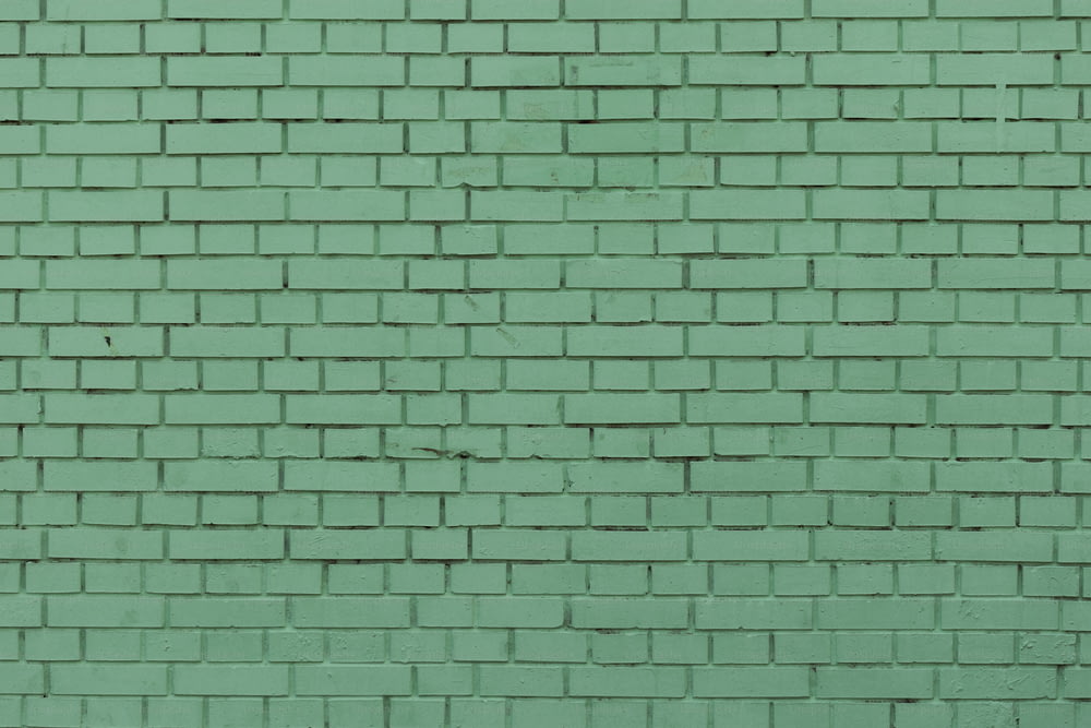 a green brick wall with a red fire hydrant