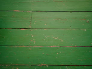 un gros plan d’un mur de bois vert avec de la peinture écaillée