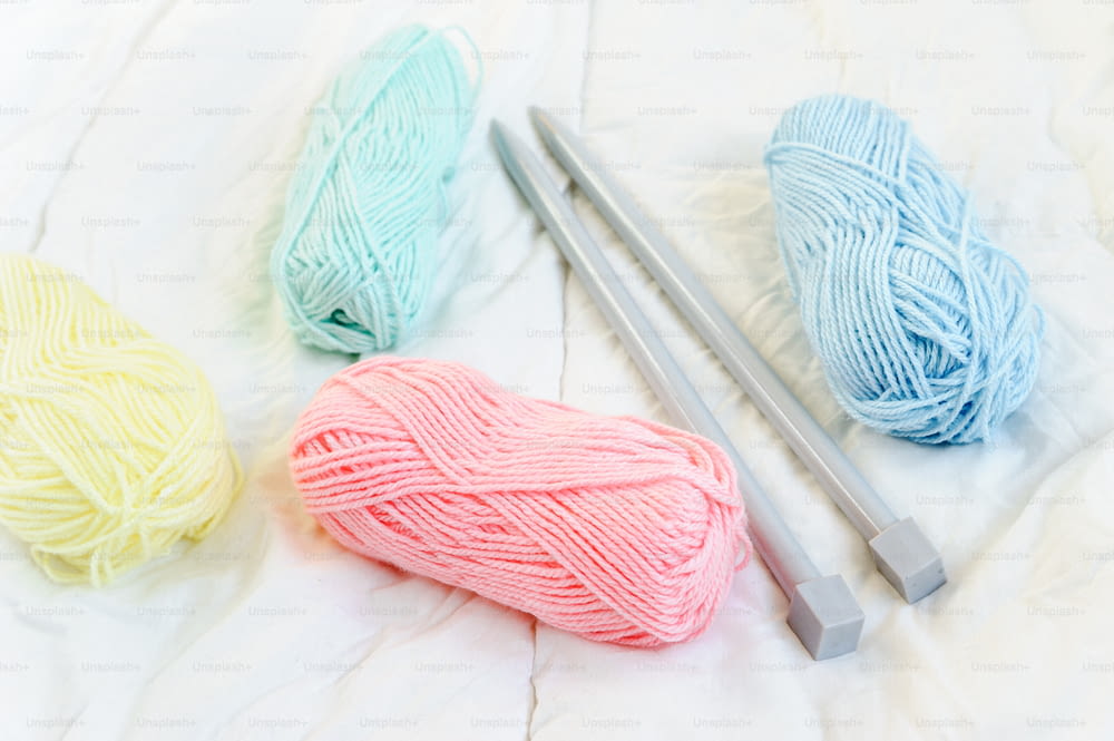 three skeins of yarn and a crochet hook on a bed
