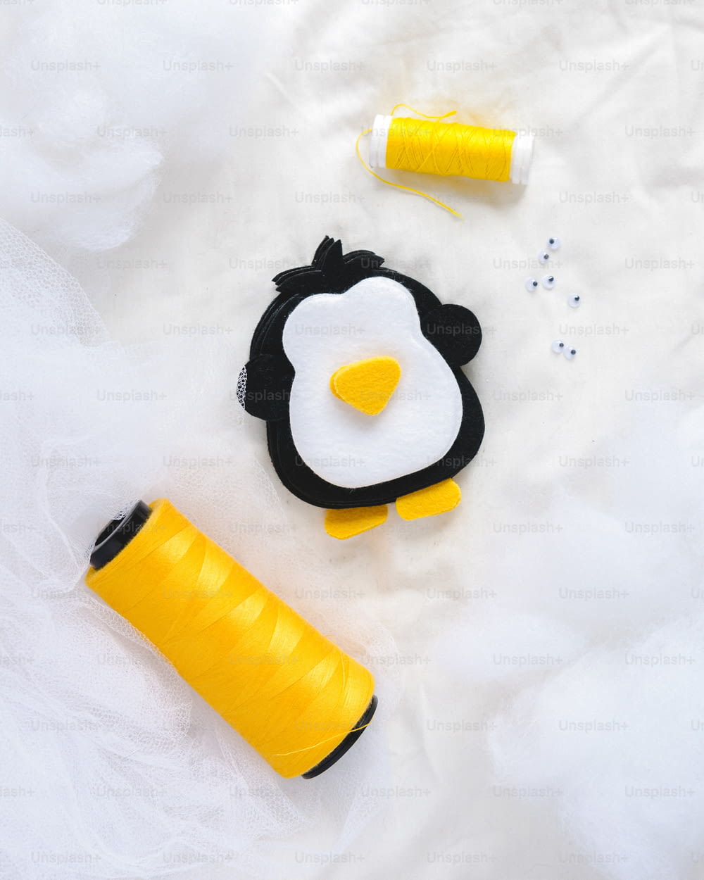 a sewing project with a penguin and a spool of thread