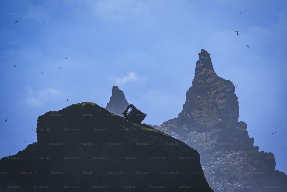 um homem sentado no topo de uma grande rocha ao lado de uma montanha