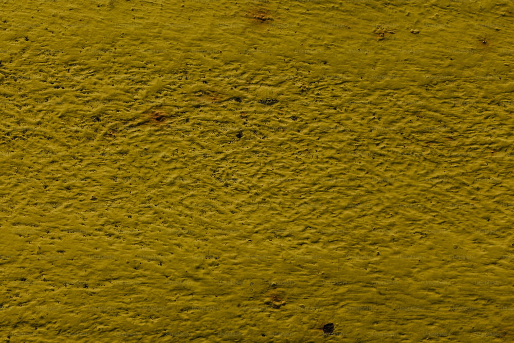 un primer plano de una pared amarilla con algo de suciedad