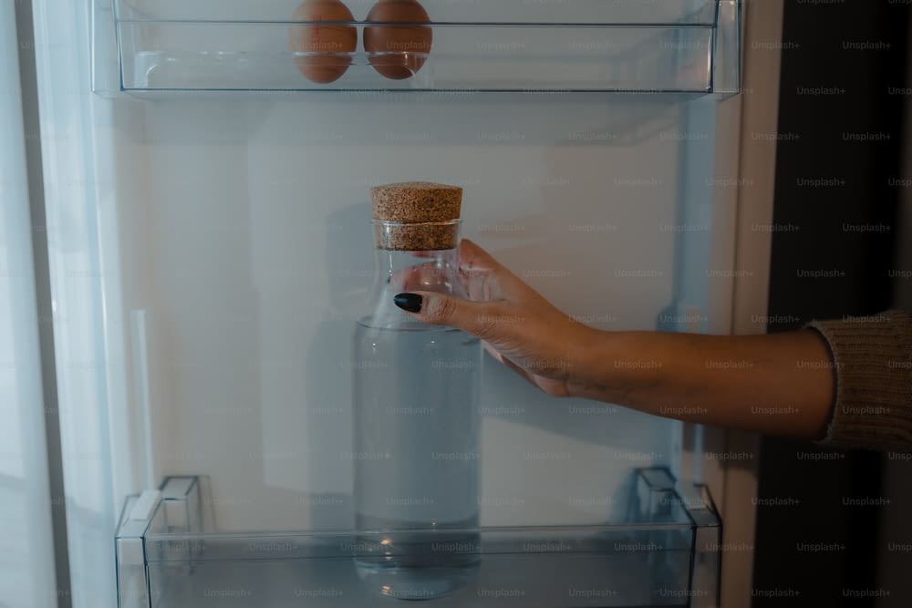 a person holding a bottle in front of a refrigerator