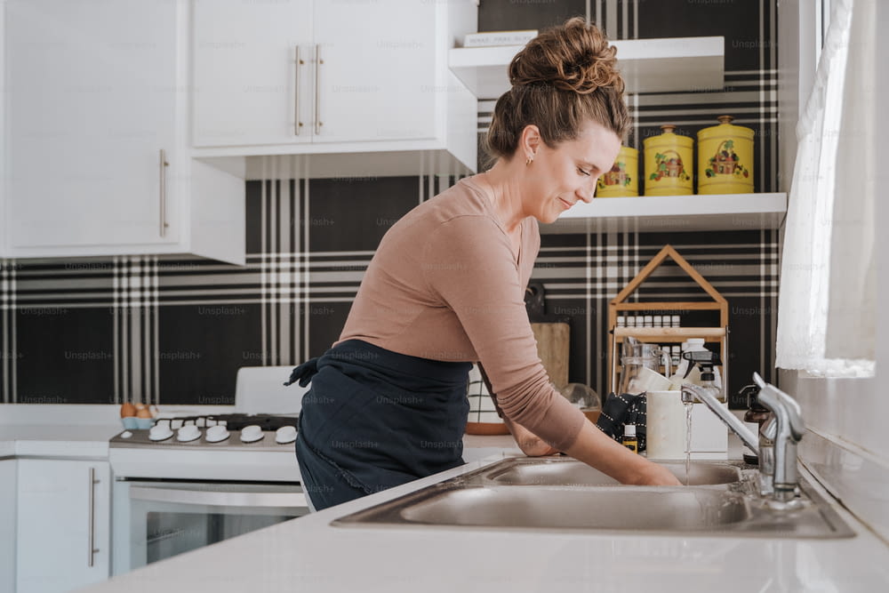 uma mulher está lavando pratos em uma cozinha