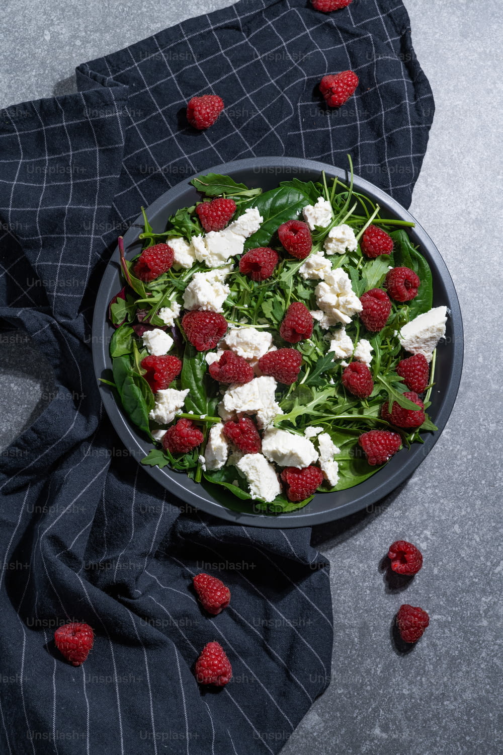 a bowl of salad with raspberries and feta cheese