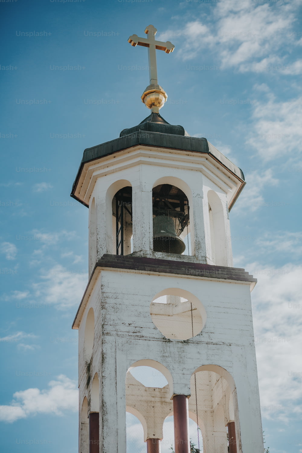 a white church bell tower with a cross on top