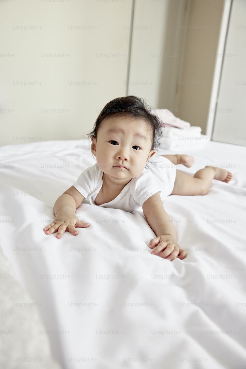 un bébé allongé sur un lit avec des draps blancs