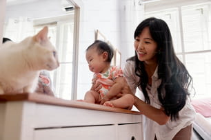 a woman holding a baby next to a cat