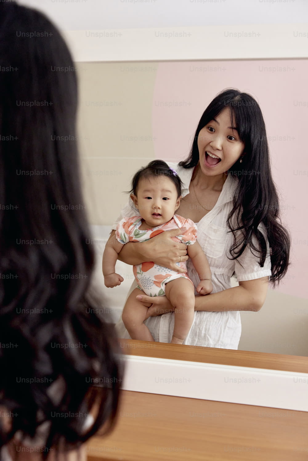 una donna che tiene un bambino davanti a uno specchio