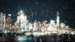 Una vista de una ciudad por la noche a través de una ventana cubierta de lluvia