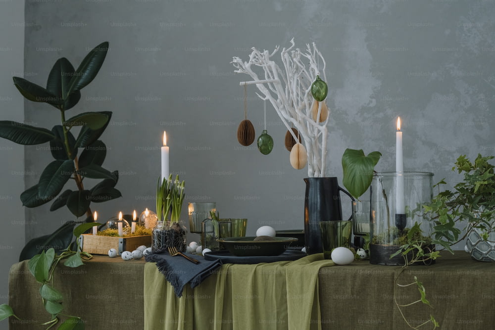 a table topped with candles and plants next to a wall