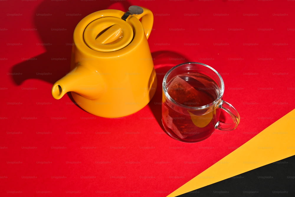 um bule amarelo ao lado de uma xícara de chá