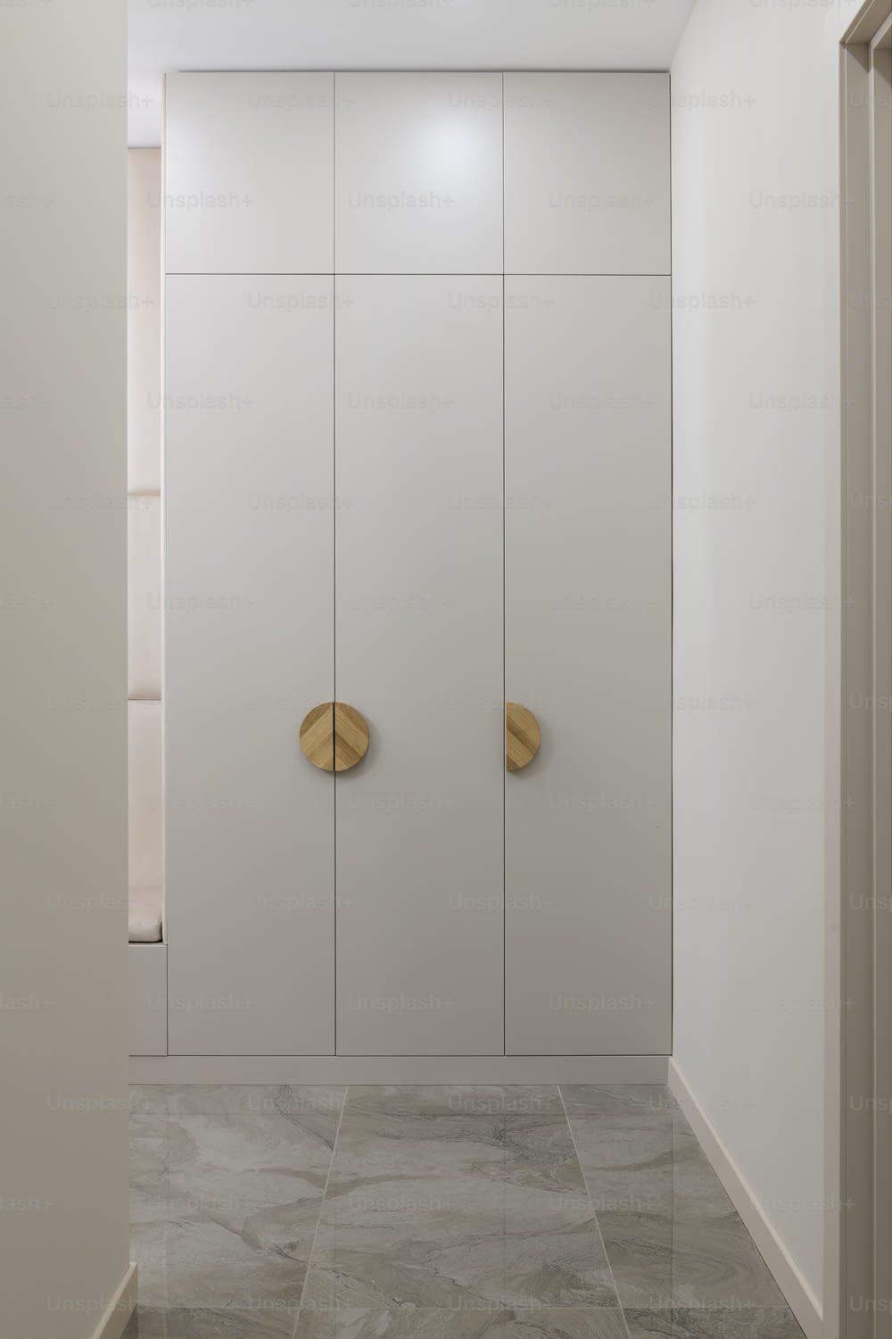 a bathroom with a white wall and two gold doors
