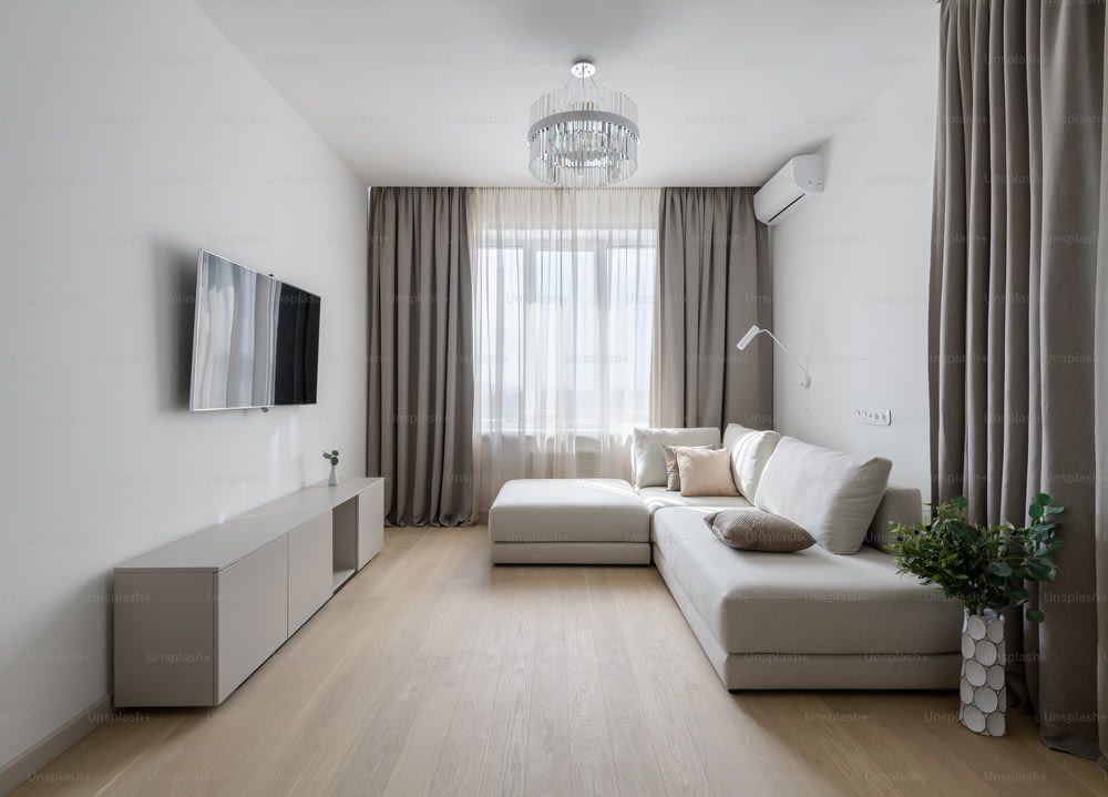 ein Wohnzimmer mit einer weißen Couch und einem Flachbildfernseher