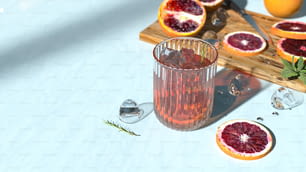 スライスしたブラッドオレンジの横にあるブラッドオレンジジュースのグラス