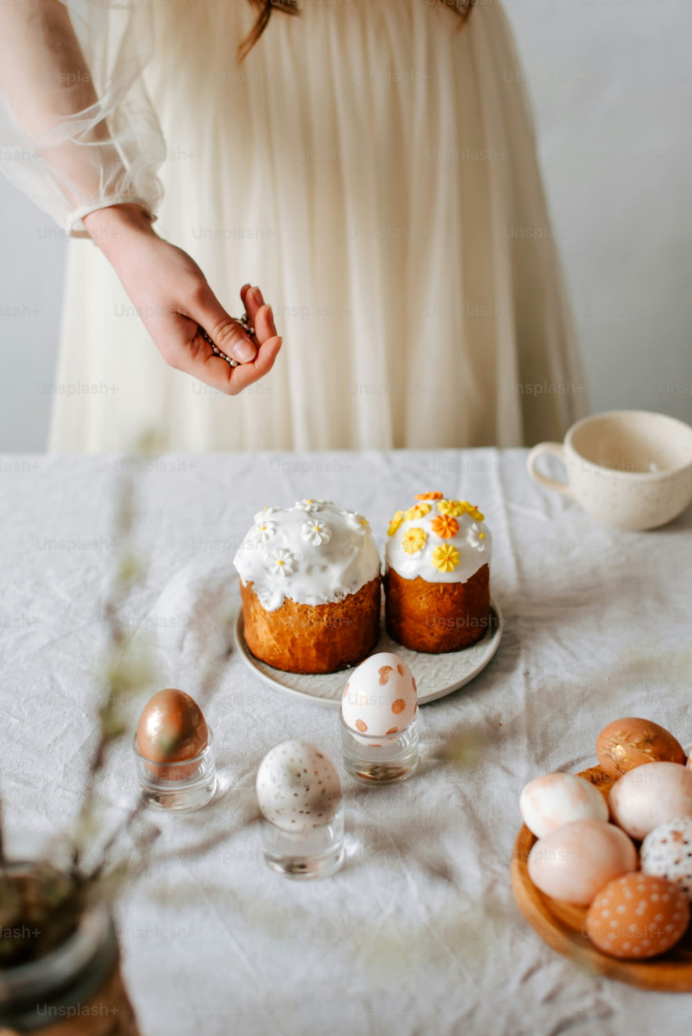 a woman in a white dress standing next to a table filled with eggs