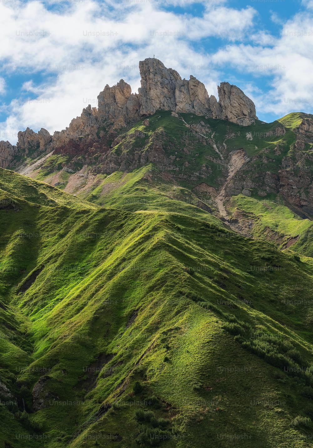 a mountain range with green grass on the side of it