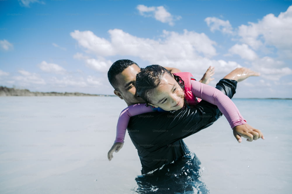a man carrying a little girl in the water