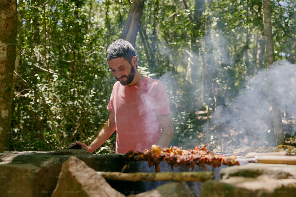 Un hombre cocinando en una parrilla en el bosque