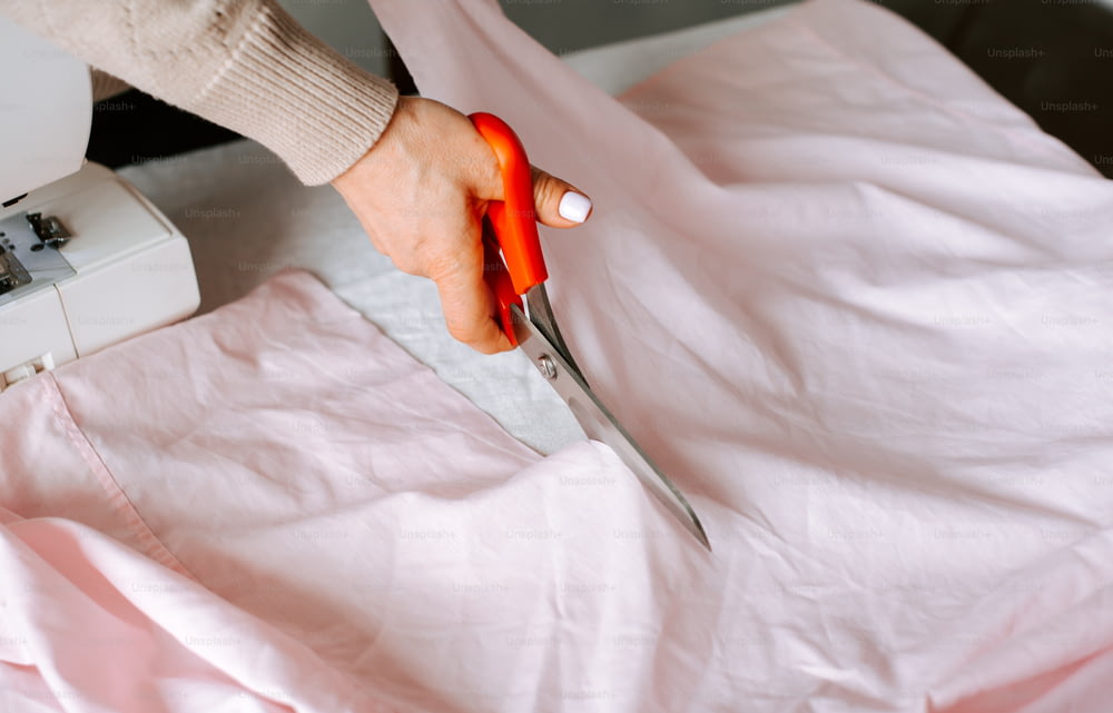 a person using a pair of scissors to cut fabric