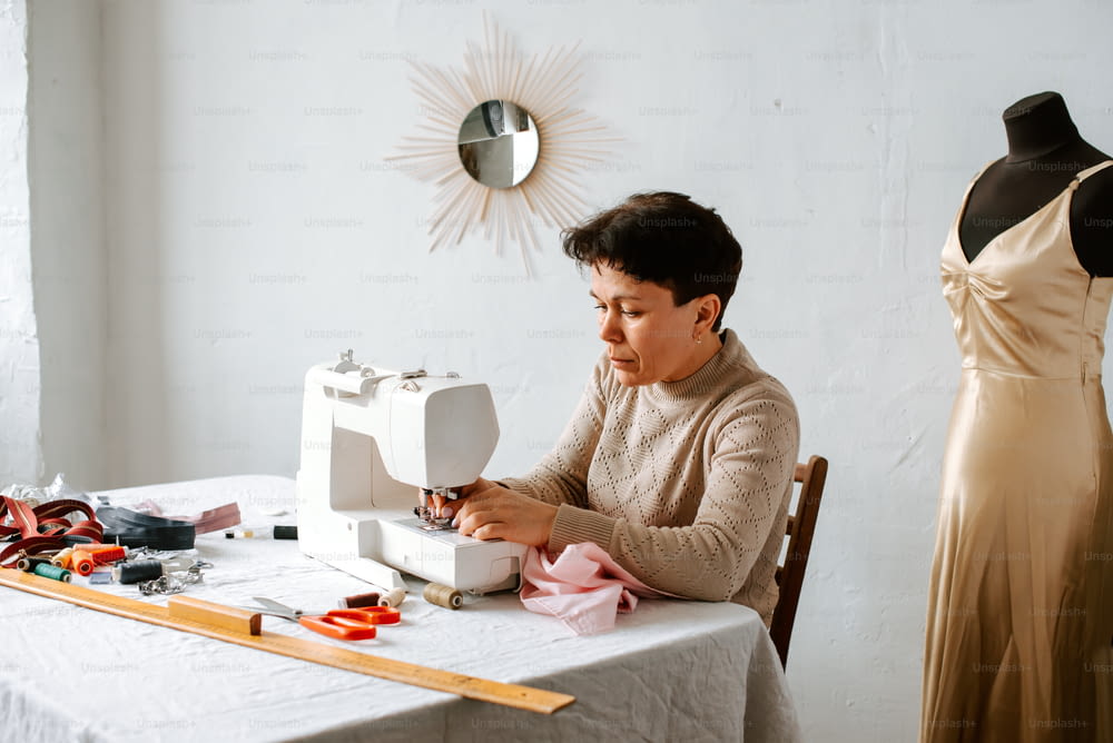 uma mulher sentada em uma mesa que trabalha em uma máquina de costura