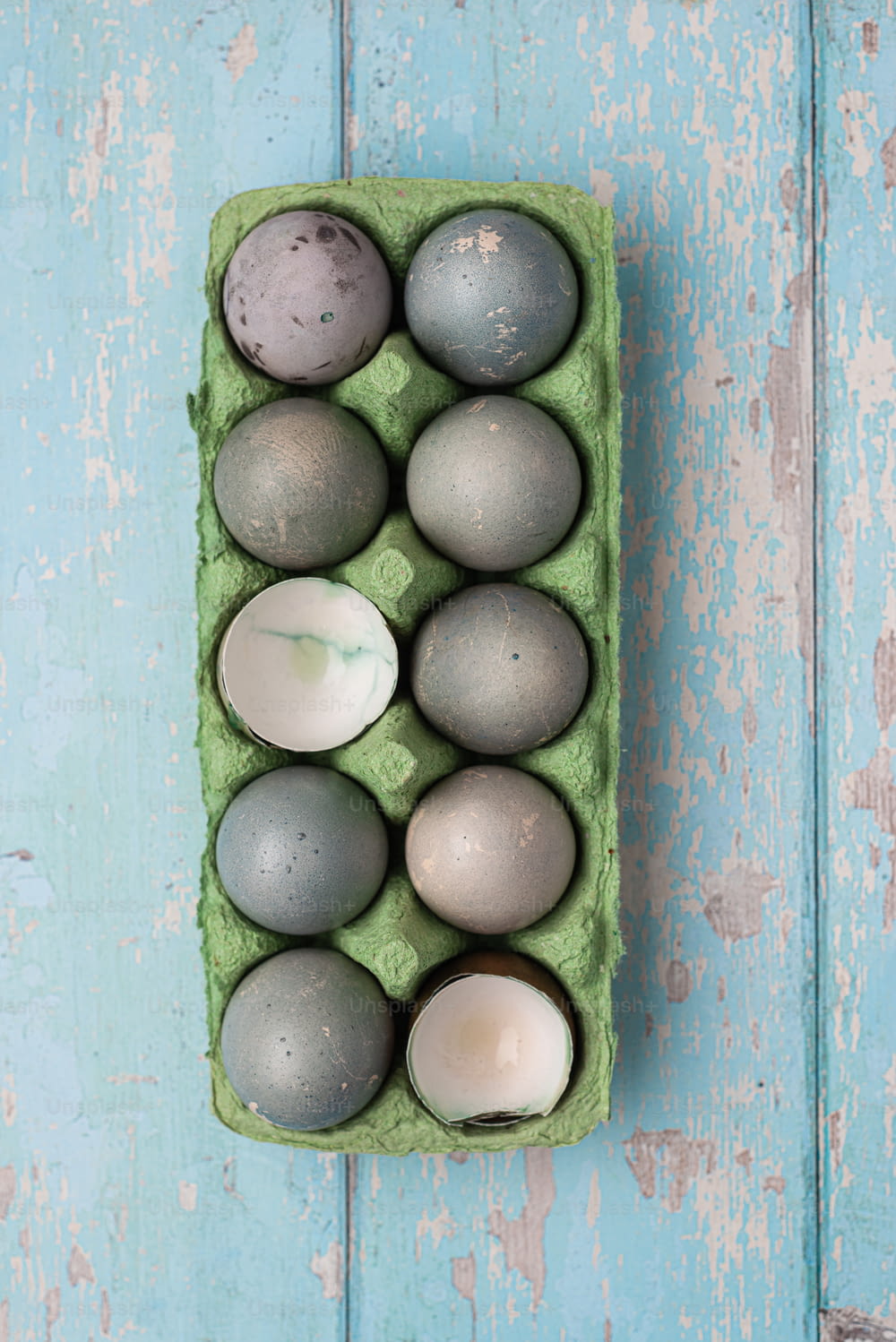 a green carton filled with gray and white eggs