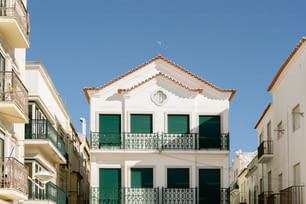 um edifício branco com persianas verdes e varandas