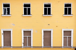 a yellow building with four windows and a bench in front of it