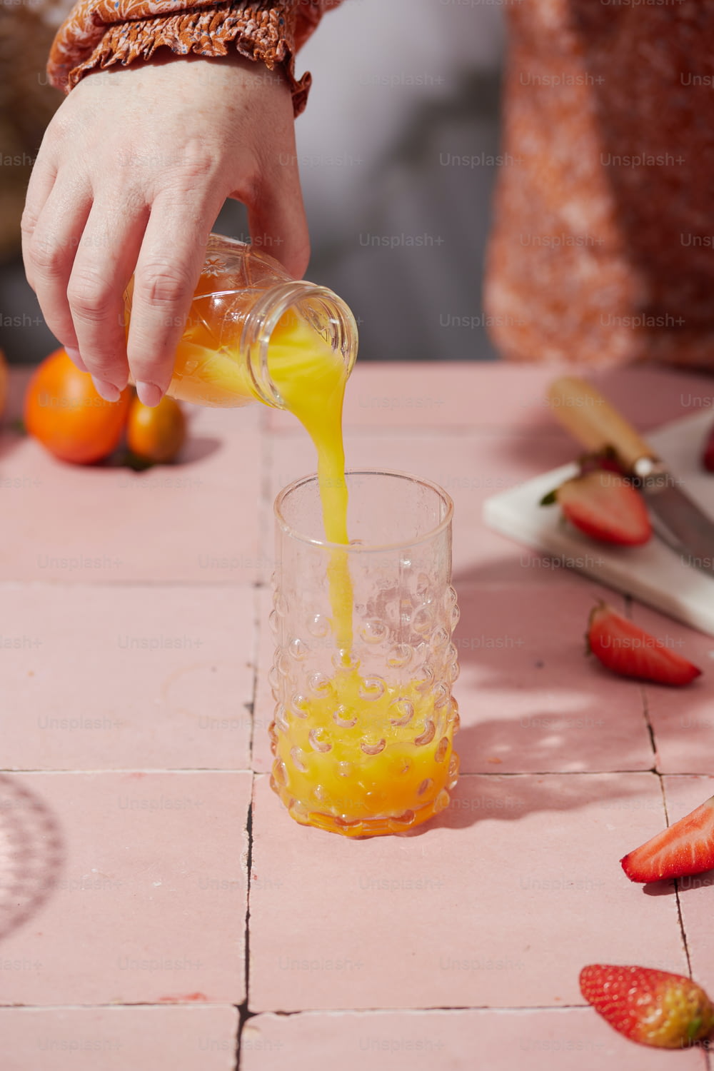 グラスにオレンジジュースを注ぐ人