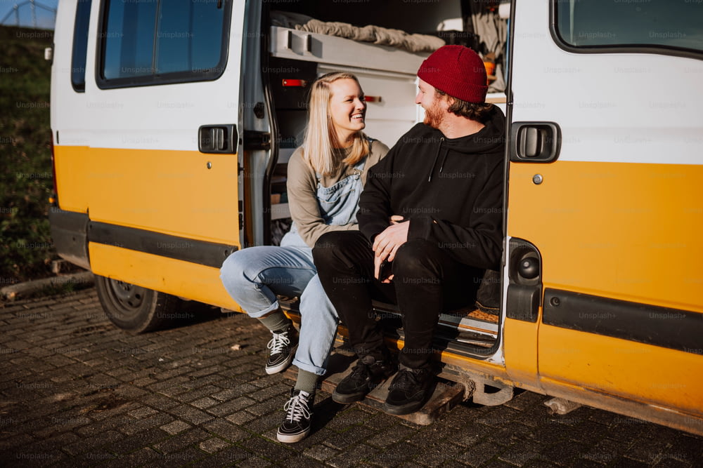 a man and a woman sitting in the door of a van