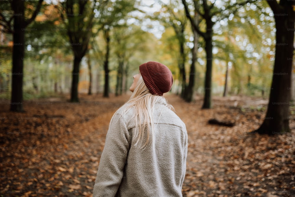 Una donna con un cappello rosso sta camminando attraverso i boschi