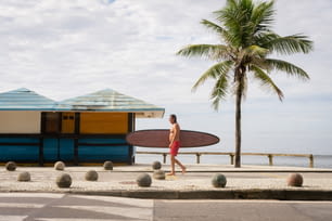 Un hombre con una tabla de surf caminando por la calle