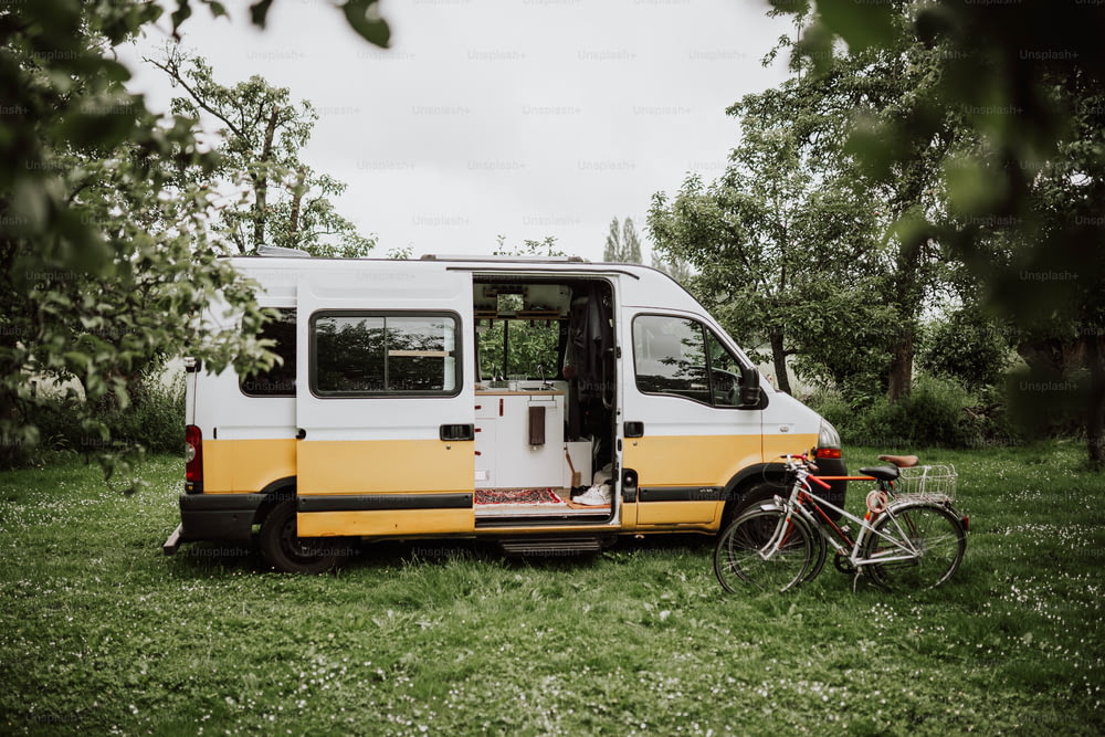uma van amarela e branca estacionada ao lado de uma bicicleta